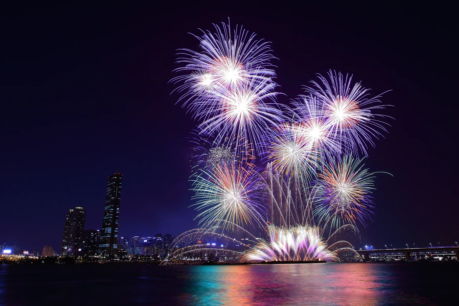 Fireworks bursting over the Han River and the Seoul skyline at night